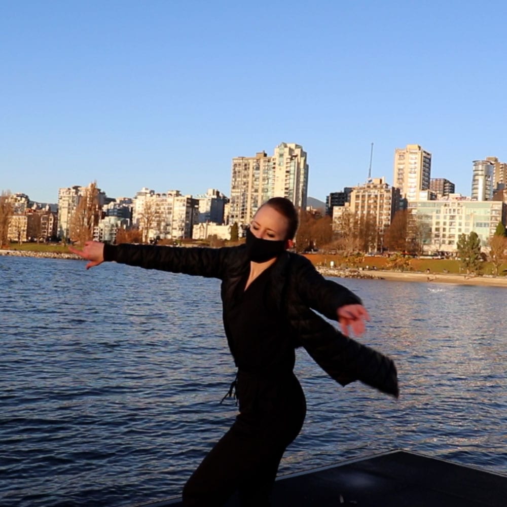 Dance artist Maria Avila performs on a dock in the Vancouver Harbour while wearing a mask
