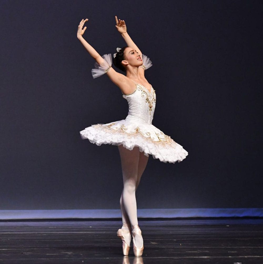 Ballerina stands on pointe wearing a full tutu