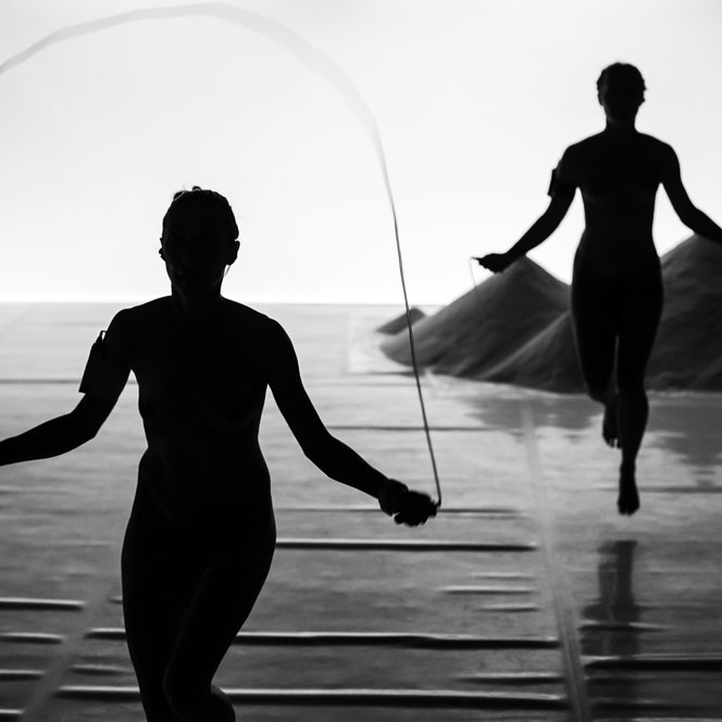 Two dance artists in silhouette jump rope