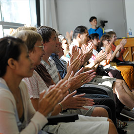 People sitting in audience in a sunny dance studio clapping