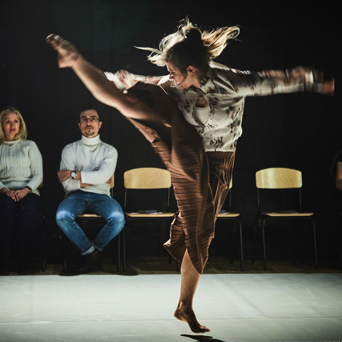 Dance artist Maria Nurmela kicks her leg up near her head mid performance