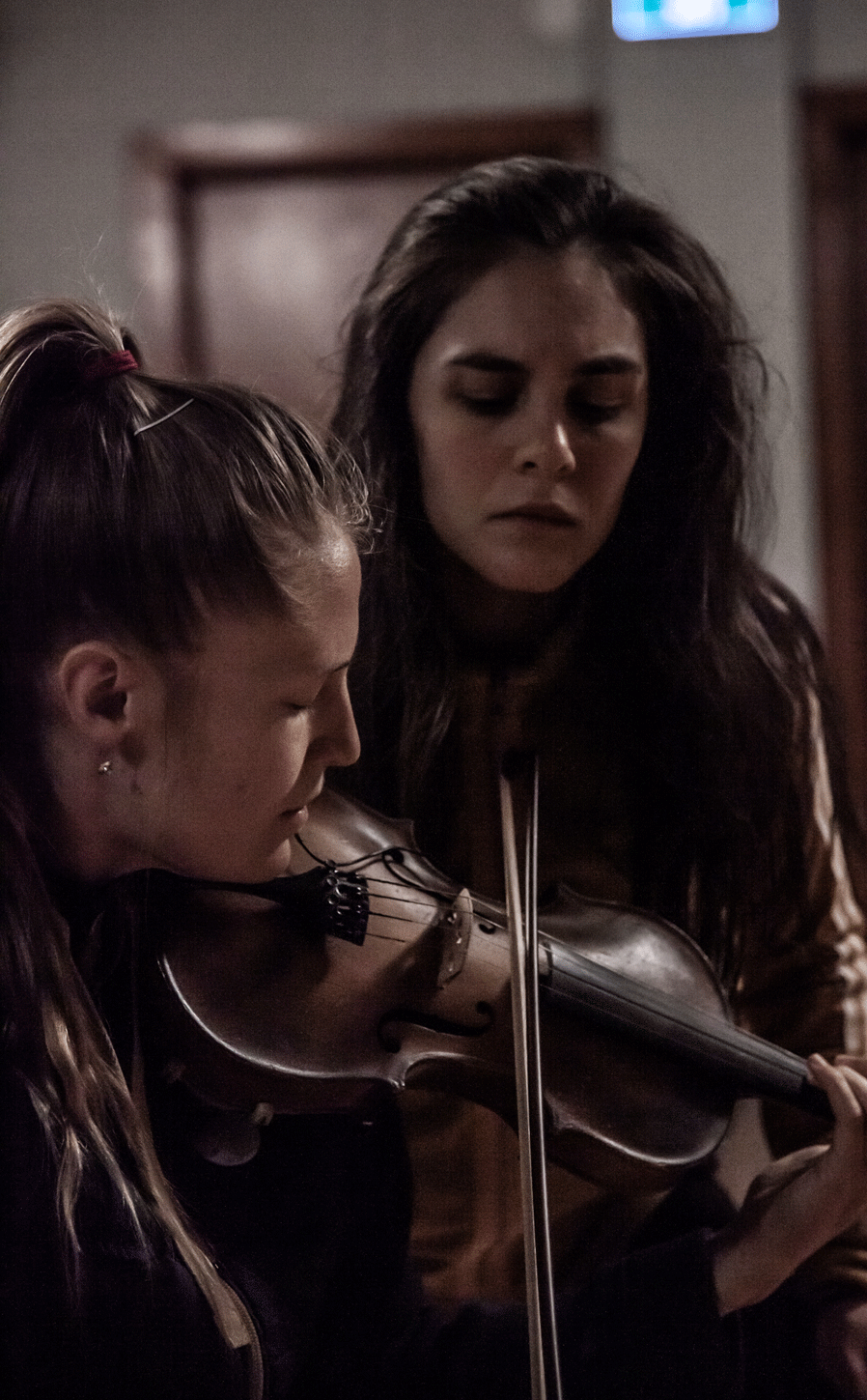 Dance artist Rebecca Margolick watches musician Hannah Epperson while she plays she plays the violin. Both have their eyes closed.